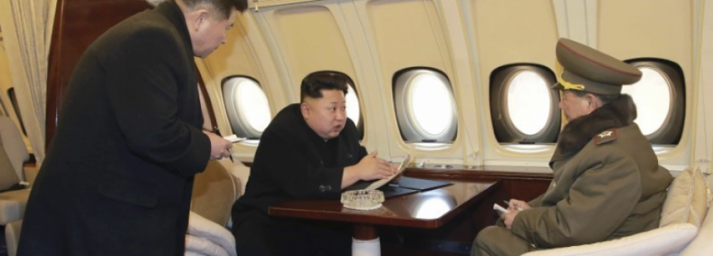 North Korean leader Kim Jong-un (C) talks with officials onboard his personal plane in this undated photo released by North Korea’s KCNA.