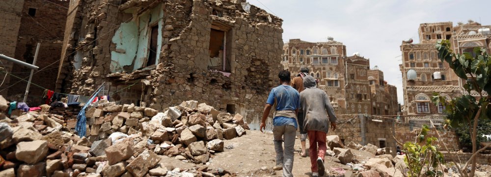 People walk past a house destroyed by an airstrike in the old quarter of Sanaa on August 8. 
