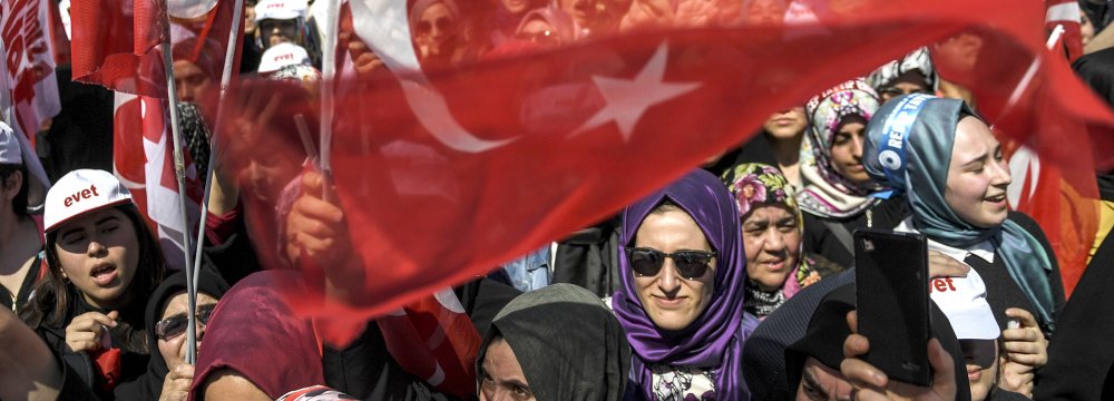 People cheer and wave the national flag as Turkey’s president delivers a speech during a rally on the eve of the constitutional referendum, on April 15 in Istanbul.