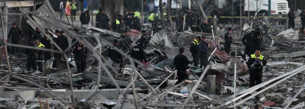 Police officers walk among the wreckage of houses destroyed in the fire at fireworks market outside the Mexican capital in Tultepec, Mexico, on Dec. 20.