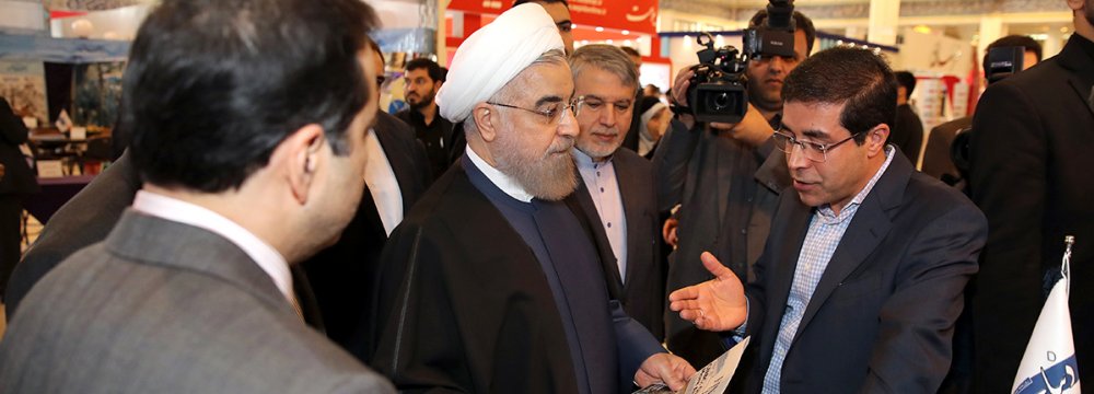Ali Reza Bakhtiari, publisher and managing director of Financial Tribune and Donya-e-Eqtesad briefs President Hassan Rouhani at the fair in Tehran on Nov. 15. 
