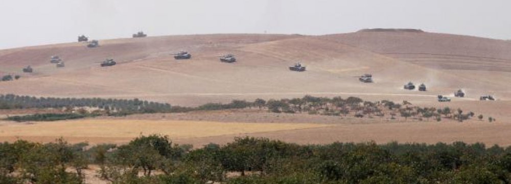 Turkish army tanks and Turkish-backed Syrian fighters make their way in the Syrian border town of Jarablus as it is pictured from the Turkish town of Karkamis, in the southeastern Gaziantep province, Turkey, August 24 .