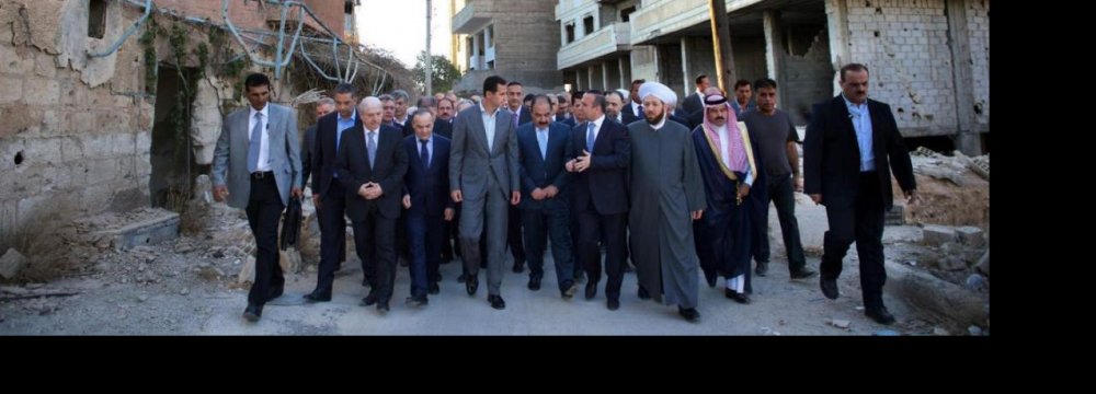 Syrian President Bashar Assad (C) walks with officials after performing the Eid al-Adha prayers in Daraya, a blockaded Damascus suburb in Syria on Sept. 12.
