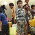 Displaced children in Yemen wait together and collect water.