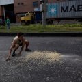 A youth moves quickly to collect grains of corn  on the street that fell from a truck that was looted outside the port in Puerto Cabello.