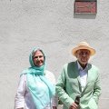 Javad Mojabi and his wife, Asieh, standing in front of the newly-installed tile on the wall of their house. Written on the plaque is: Javad Mojabi, Poet, Writer and Journalist; Lives Here Since 1970