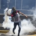 A demonstrator returns a tear gas during clashes with riot police in eastern Caracas on April 8.